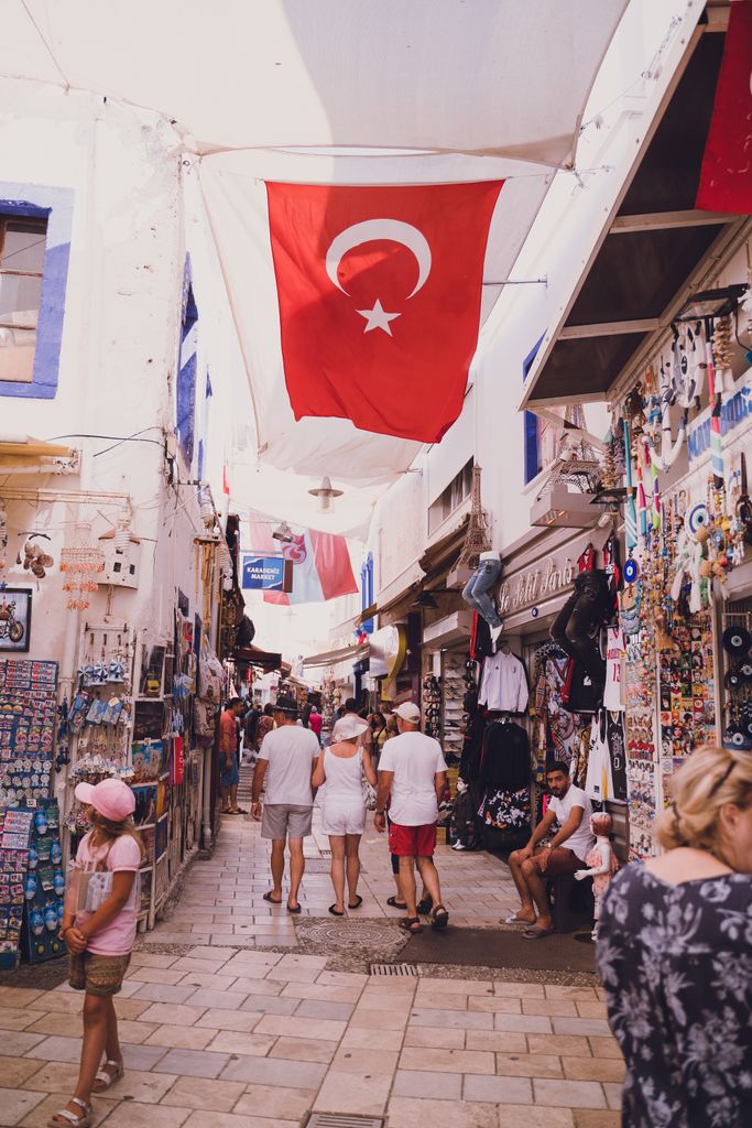Bustling street market in Bodrum with Turkish flags and diverse souvenirs for sale.